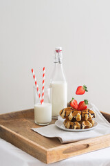 Belgian waffles and strawberry with a glass of milk on a wooden tray, levitation