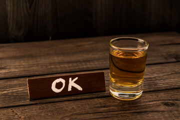 Glass of tequila with the wooden plank on it is an inscription 