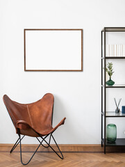 Living room, chair with bookcase. Blank picture frame mockup in interior design. View of modern...