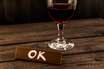 Glass of red wine with the wooden plank on it is an inscription 