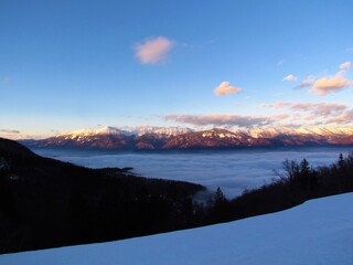 Karavanke mountains in Gorenjska, Slovenia at sunset in winter and fog covering the basin bellow