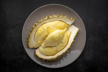 yellow durian monthong flesh in ceramic plate on dark texture background, king of fruits