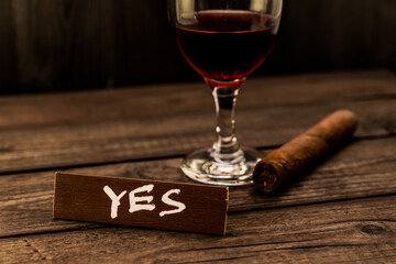 Glass of red wine with cuban cigar and the wooden plank on it is an inscription 