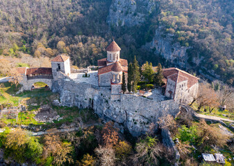 Fototapeta na wymiar Picturesque aerial view of Georgian Orthodox Motsameta monastery on stone cliff covered with forest located near Kutaisi at Imereti region on sunny spring day