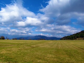 Fototapeta na wymiar View of Slivnica hill in Notranjska, Slovenia and a field in front with white clouds in blue sky