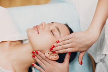 Beautiful young woman getting face treatment massage at beauty spa
