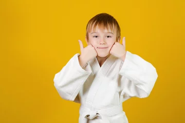 Fotobehang Happy boy in white kimono practices judo. Spirit of martial arts. Martial arts concept. © volurol