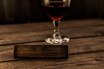 Glass of red wine with the empty wooden plank on an old wooden table. Angle view, focus on the wooden plank