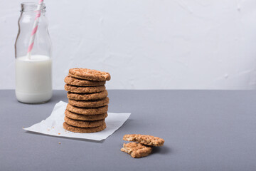 Biscotti integrali per colazione con latte in bottiglia e una  cannuccia rosa sullo sfondo chiaro