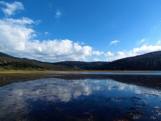 Scenic view of beautiful lake Cerknica or Cerknisko jezero in Notranjska region of Slovenia with white clouds in blue sky and a reflection in the lake