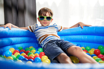 Obraz premium Portrait of relaxed boy in an inflatable ball pool