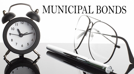 MUNICIPAL BONDS text. Glasses and pencil and alarm clock