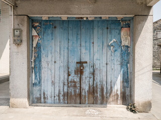 old worn wooden blue door with decaying Chinese decorations banners