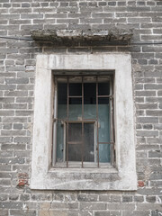 old window with rusty metal bars in ancient brick wall of 200 year old Chinese building