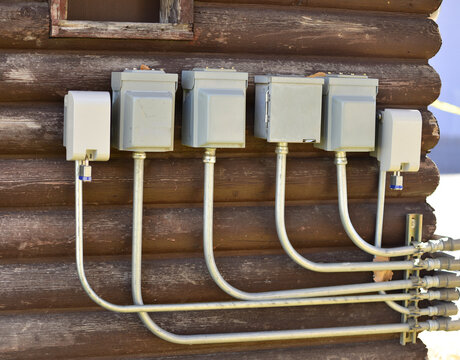 Electrical boxes and conduits outside on wall of old log building.