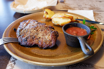 meat steak on a plate with potatoes and sauce. dinner at a restaurant.