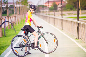 Young Asian cyclist take a rest after cycling on bike path, healthy lifestyle concept.