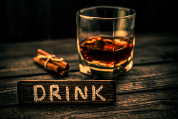 Glass of brandy with cinnamon sticks tied with jute rope and the wooden plank on it is an...