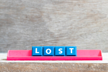 Tile letter on red rack in word lost on wood background