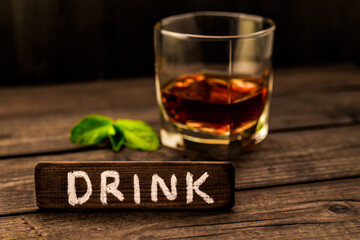 Glass of brandy with mint sprig and the wooden plank on it is an inscription 