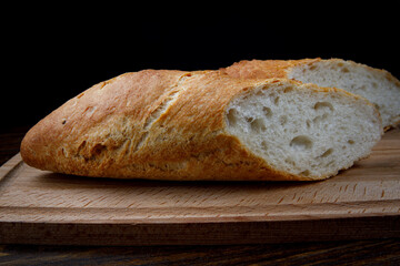 Sliced fresh crispy baguette on a wooden cutting board. art bread.