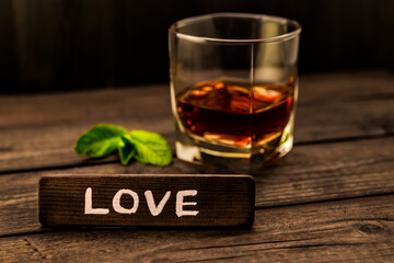 Glass of brandy with mint sprig and the wooden plank on it is an inscription 