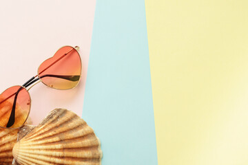 summer vacation concept with heart shape sunglasses and sea shells on pastel background