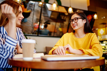 Cheerful diverse women interacting in cafe
