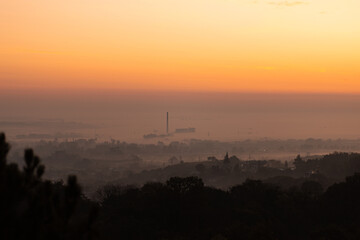 Beautiful sunset over city skyline. Golden hour closeup with layers of fog