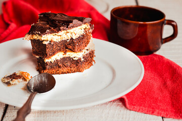 Slice of three chocolate cake on a plate. Delicious tasty homemade cake on table. White wooden background. Young woman eating dessert process