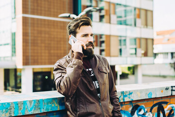 young bearded man talking smartphone serious