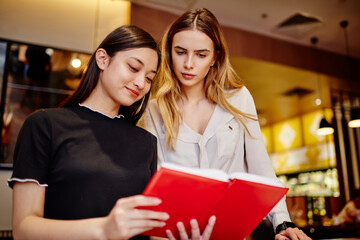 Young diverse women reading information in notebook