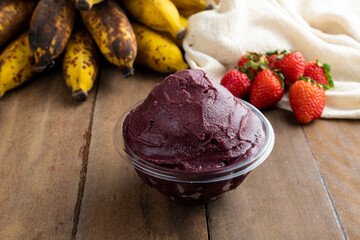 Açai, Brazilian frozen açai berry ice cream bowl with strawberries and bananas. with fruits on wooden background. Summer menu front view