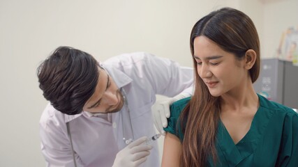 Medical young in safety gloves is making a vaccine injection to a female patient in a health...