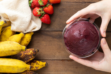 Açai, Woman holding an Brazilian frozen açai berry ice cream bowl. with fruits on wooden...