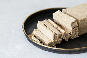 Sliced halva in a black plate on a white background. Sunflower halva close-up. Oriental dessert.