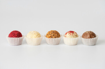 Homemade candies or energy balls with chocolate, coconut, karkade and dried fruit on a white background. Copy space.