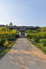 Korean Confucian Academy from Joseon Dynasty era. Path with small trees leading to main gate with pavilion behind. Byeongsan Seowon, Andong, South Korea. Translation: "Bongnyemun - Main Gate"