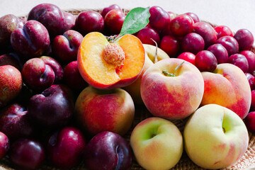 peach, plum and cherry plum in a wooden basket on table.
