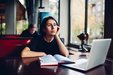 Dreamy woman looking away working in cafe