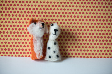 a red fox and a spotted white and brown dog finger puppet posing against a red polka dot and yellow background