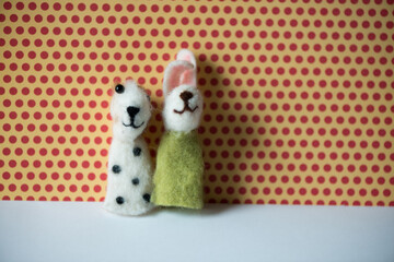 a spotted white dog and a rabbit finger puppet posing against a red polka dot background