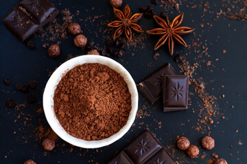 Chocolate chunks cocoa powder and spice on dark slate table