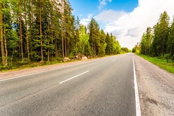 Rural road passing through the forest. View from the side of the road