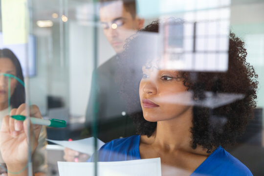African american woman writing on glass board at modern office