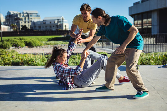Three happy caucasian female and male friends messing around in the sun