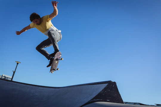 Caucasian man jumping and skateboarding on sunny day - Powered by Adobe
