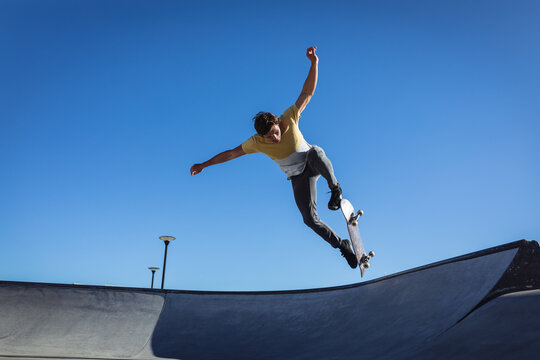 Caucasian man jumping and skateboarding on sunny day
