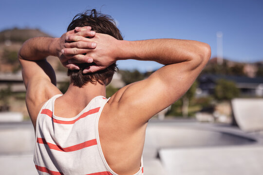 Back view of caucasian man resting with hands behind head - Powered by Adobe