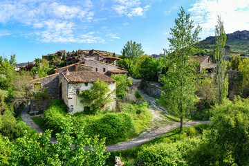 Fototapeta na wymiar Aerial view of old town in the mountains with stone houses and green trees. Patones de Arriba Madrid.
